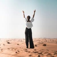 A woman with her arms raised in the desert